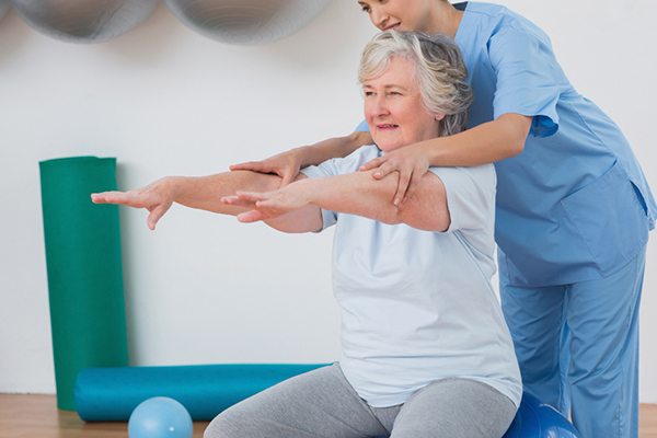 Enfermera al cuidado del adulto mayor le ayuda a ejercitarse